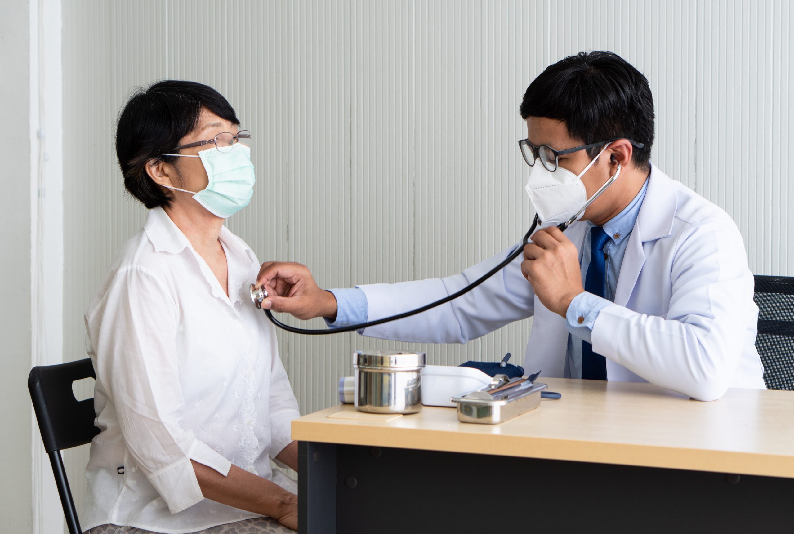asian doctor using stethoscope to exam the woman patient who come to visit at hospital for sickness. healthcare and medical concept